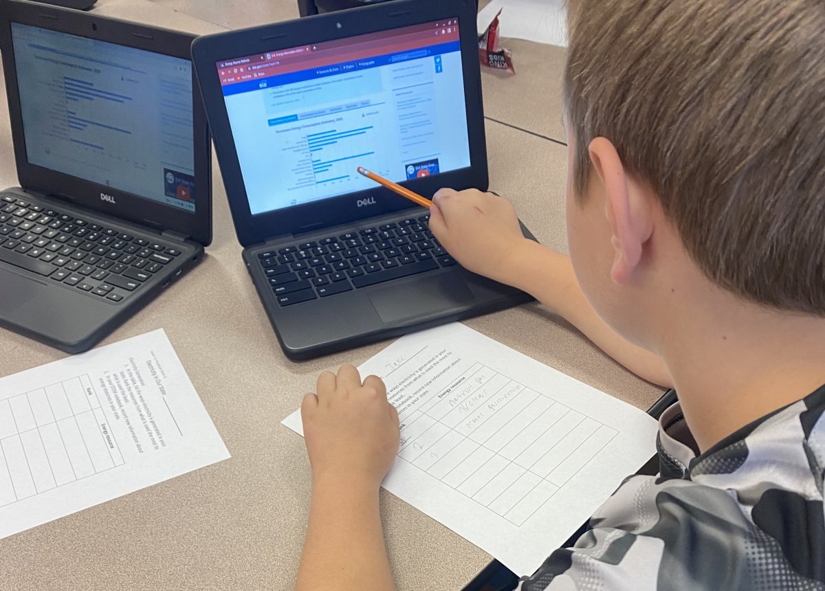 fourth grade student pointing at bar graph on computer monitor