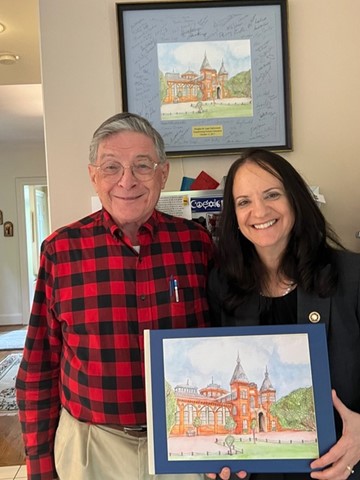 Carol O’Donnell stands with Doug Lapp, founder of the Smithsonian Science Education Center. Carol is holding a book with an illustration of the Smithsonian Castle