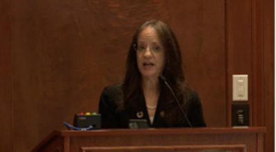 Carol O’Donnell provides remarks at a podium.