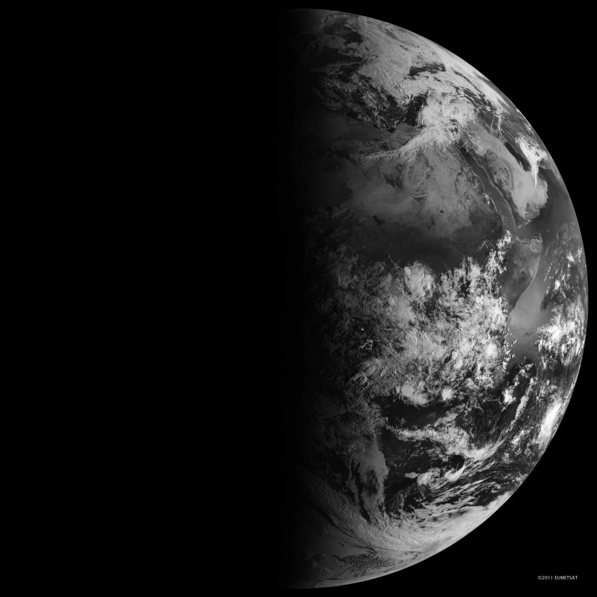 Black and white image of Earth with half illuminated by sunlight and half in darkness