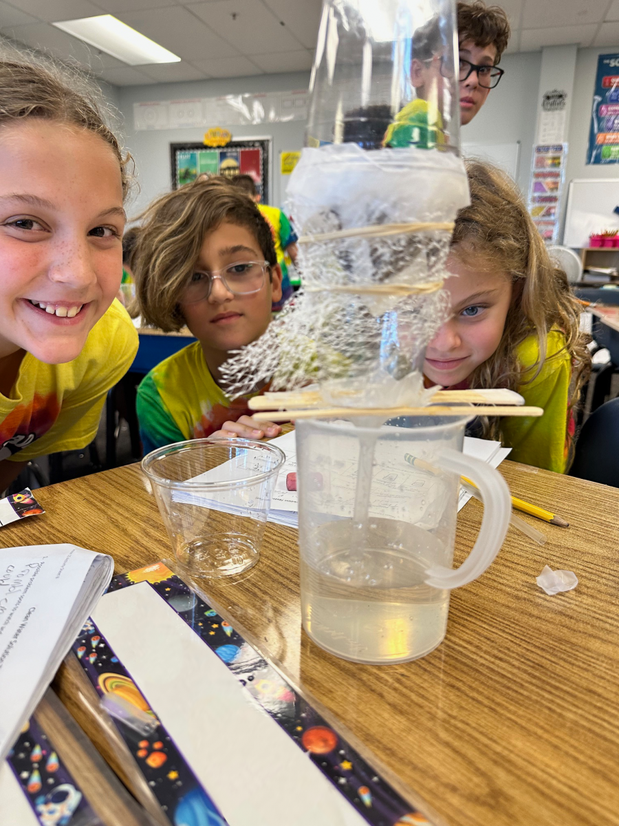 Three children observe a designed solution.