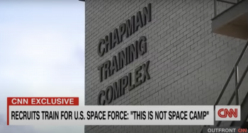 The side of a building with lettering that says Chapman Training Complex and a news title across the bottom that says this is not space camp.