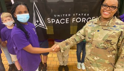 Woman soldier shaking hands with a student