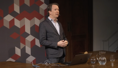 Man standing at a desk giving a lecture