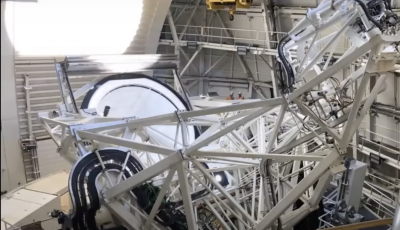Image of the interior of an observatory with white metal structure looking down at the primary mirror of the telescope.