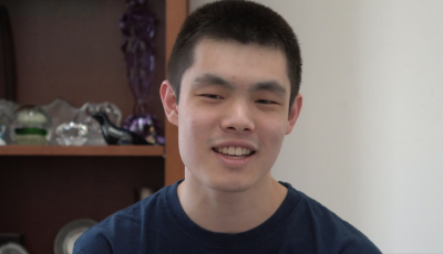 Man looking at camera with bookshelf behind him.