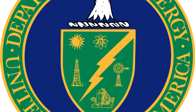 A blue circle with an eagle head above a green shield with a green ring around the circle with text that says Department of Energy United States of America.