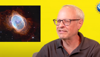 A yellow rectangle with a man in the center looking at an inset image of an image from the James Webb space telescope of the southern ring nebula that is blue oval with red radiating from it.