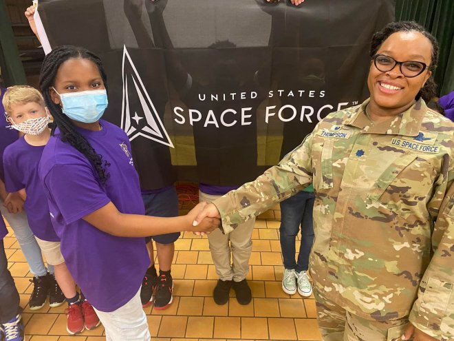 Woman soldier shaking hands with a student
