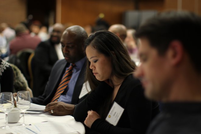 A workshop participant is deep in thought at a table with her peers.
