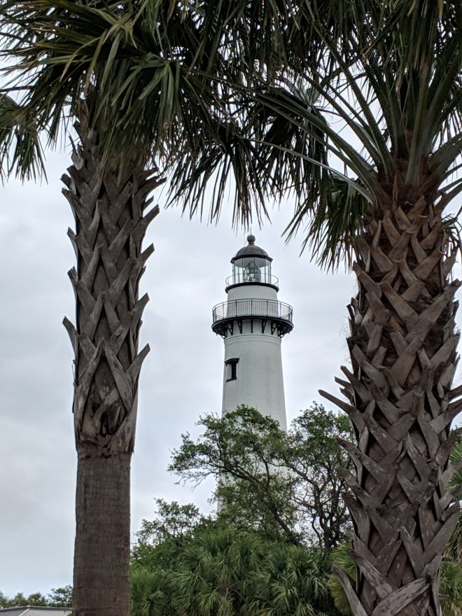 A lighthouse between two palm trees