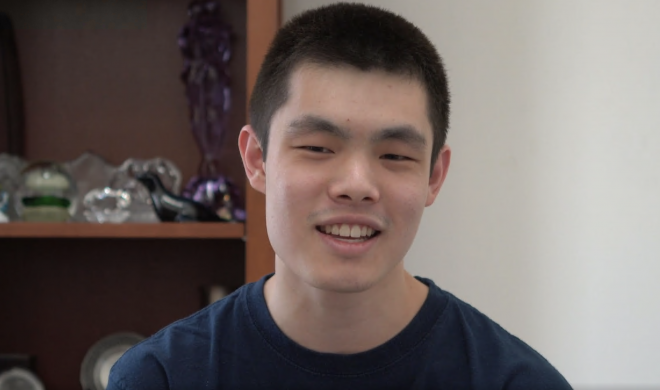 Man looking at camera with bookshelf behind him.